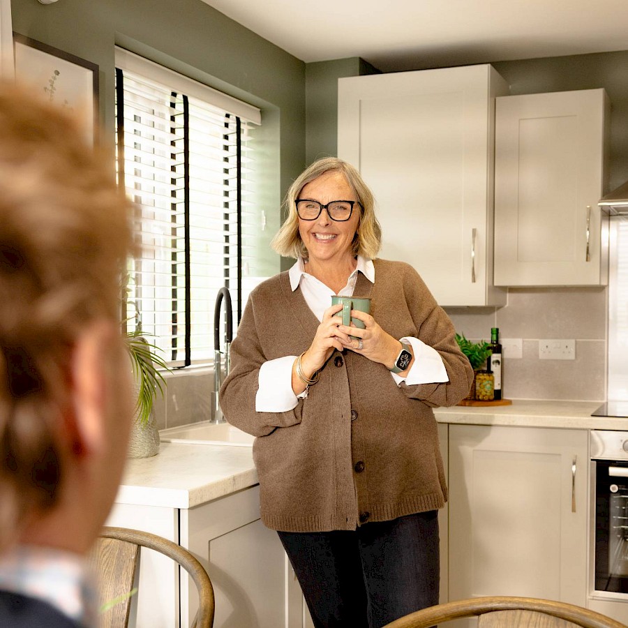 Woman smiling in kitchen with drink in hand