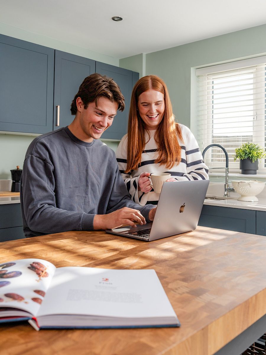 Young couple looking at laptop in kitchen