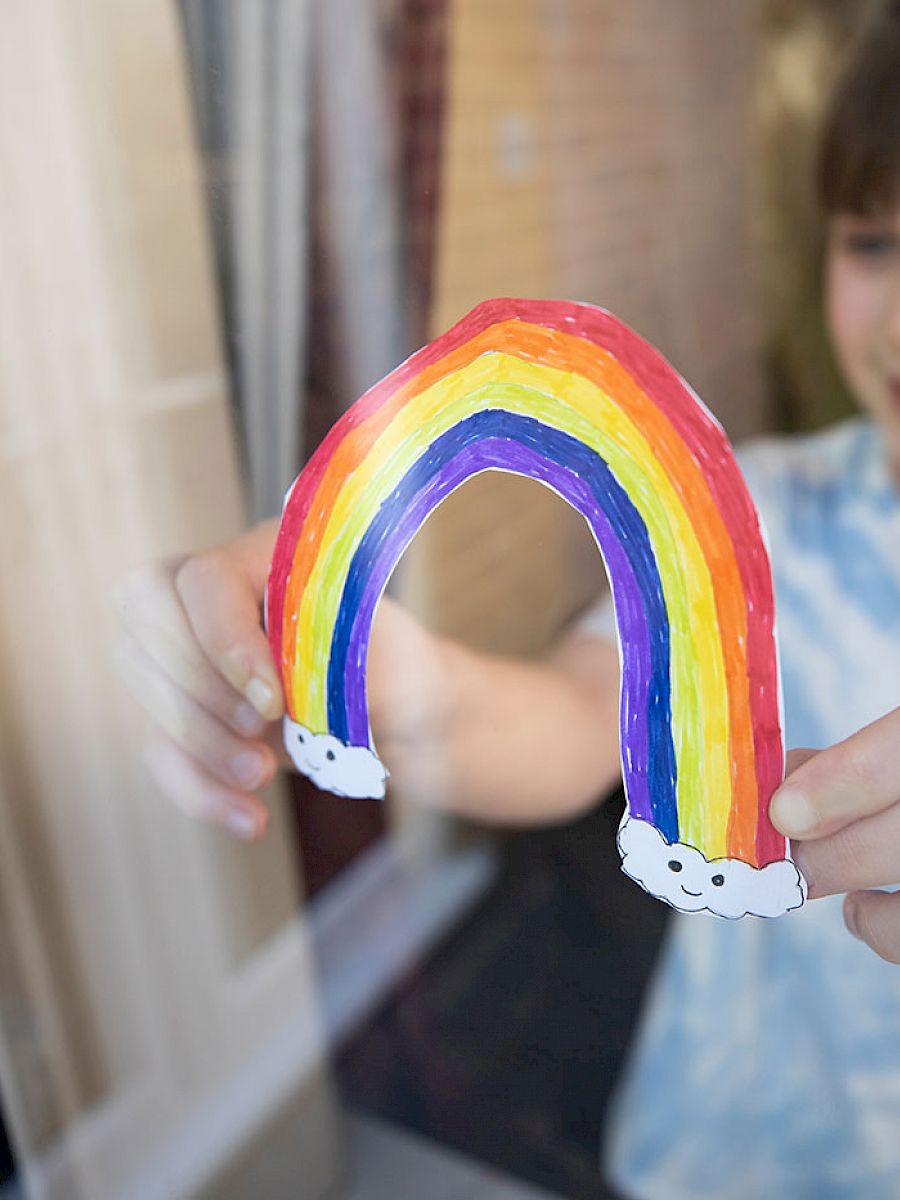 Girl sticking a hand drawn rainbow to her window
