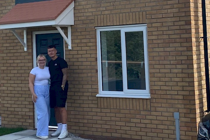 Young couple standing outside their front door