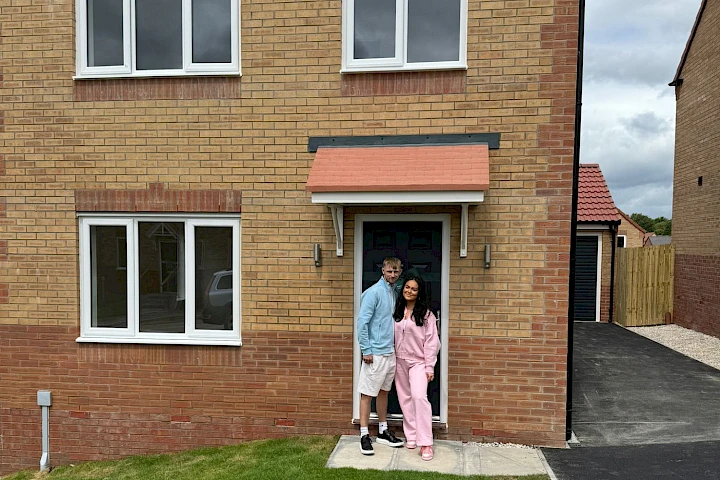 Young couple standing outside the front door of their home
