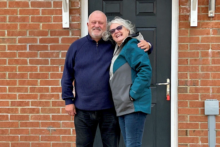 Man and woman stood outside the front door of their home