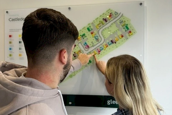 Young couple pointing at their reserved plot on a development site map