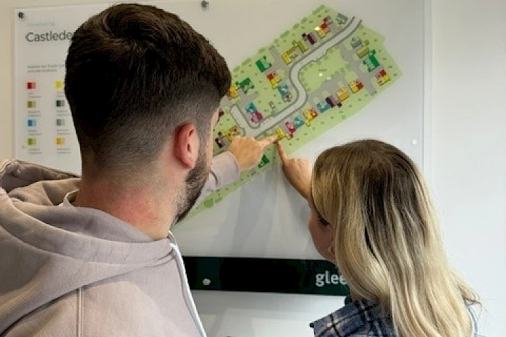 Young couple pointing at their reserved plot on a development site map