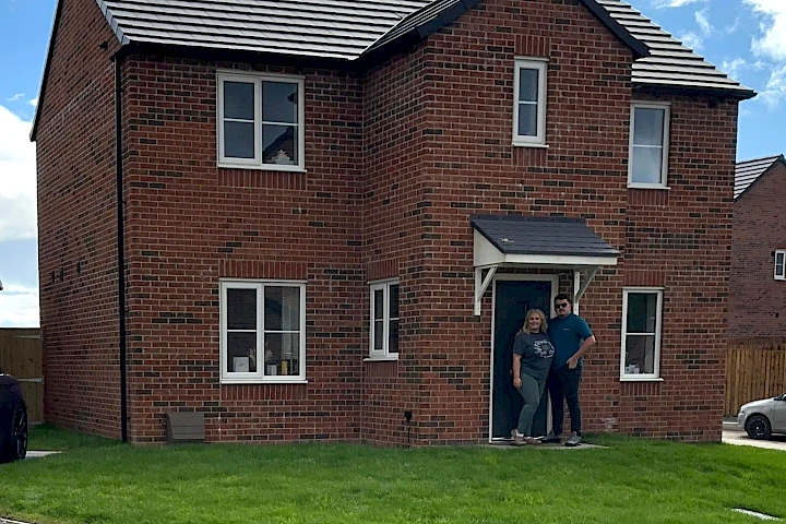 Happy homeowners stood in front of their front door