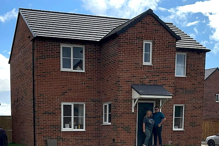 Happy homeowners stood in front of their front door