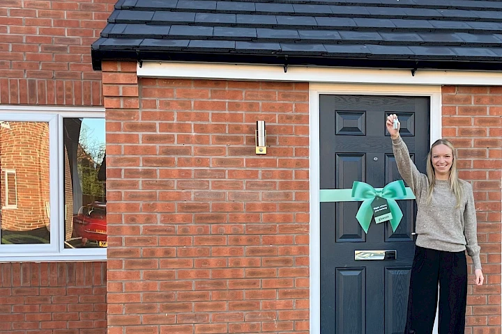 Happy solo homeowner smiling with keys outside of new home