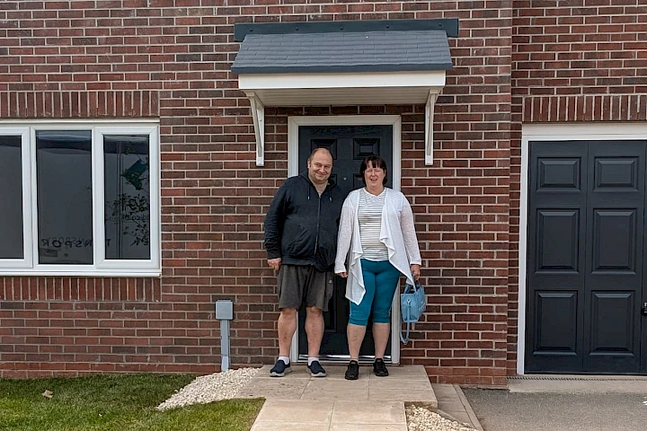Couple stood outside their new home smiling
