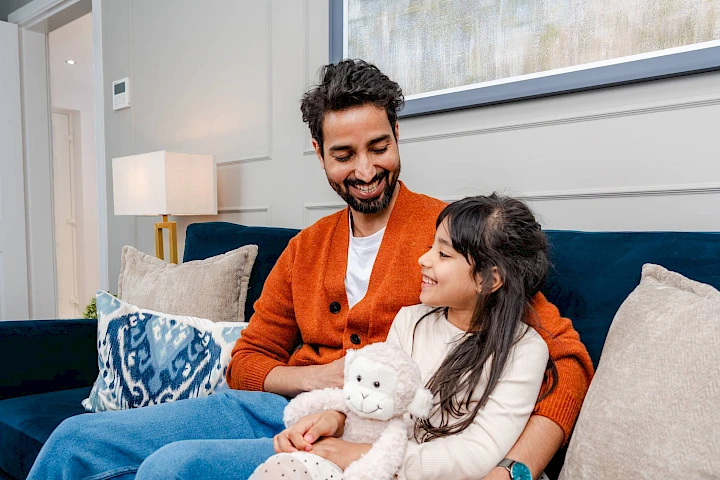 Man and little girl on sofa together smiling