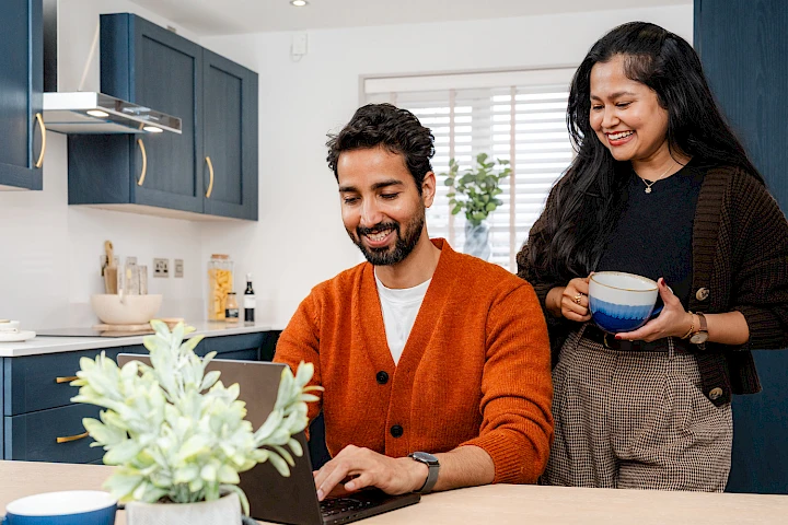 A young couple working from a laptop in the kitchen