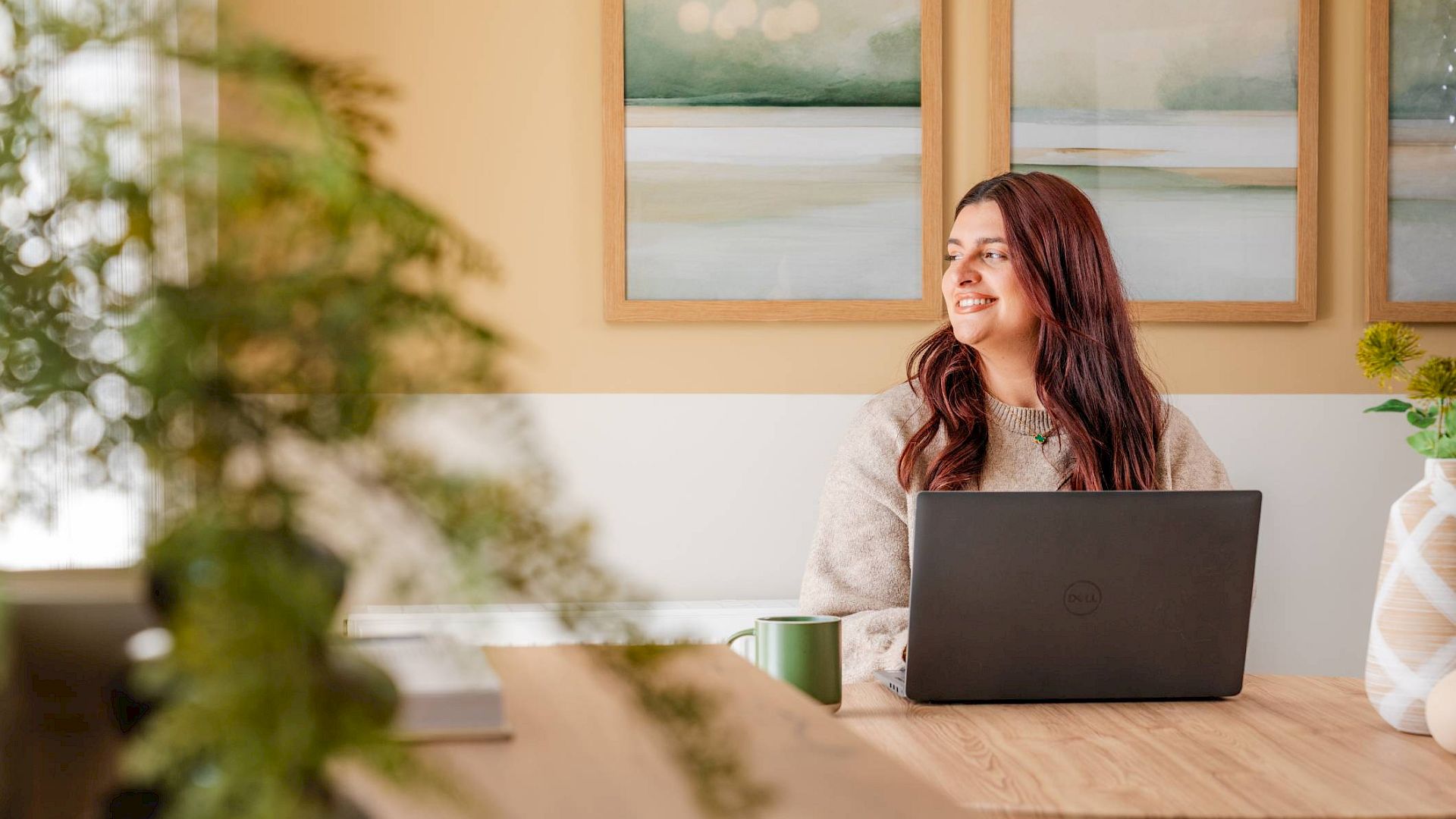 Young woman sat with laptop in kitchen